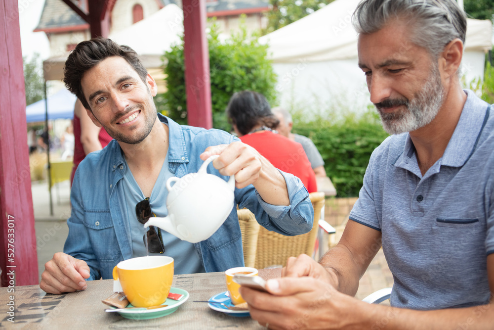 smiling men drinking tea outdoors smiling men drinking tea outdoors