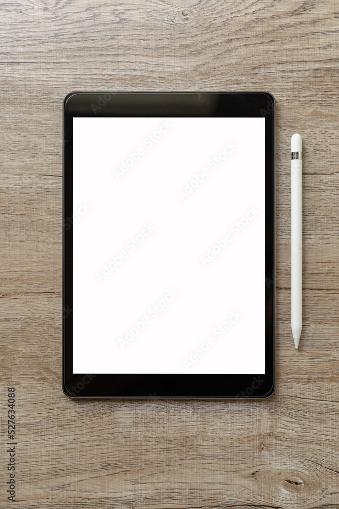 Black tablet with white blank screen is on top of brown paper with supplies. Top view, flat lay. Black tablet with white blank screen is on top of brown paper with supplies. Top view, flat lay.