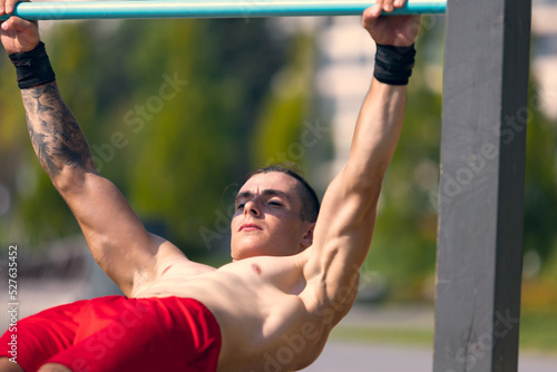 Workout. Strong muscular man, student training, practicing at sport ground at public park in summer morning, outdoors. Action, skills, challenges