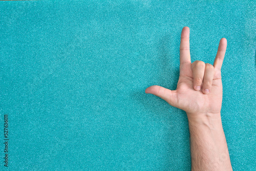 man hand skate horns gesture on turquoise background