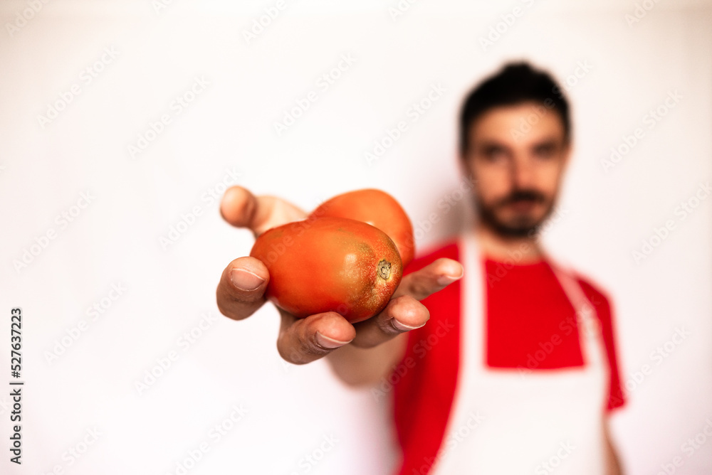 Caucasian man holds red tomatoes in his hand. Healthy food for diet, man with red t-shirt on out of focus white background. Caucasian man holds red tomatoes in his hand. Healthy food for diet, man with red t-shirt on out of focus white background.