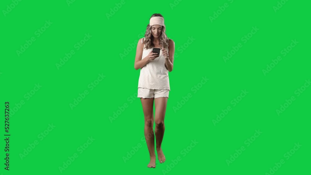Front view of walking barefoot woman in pajamas using smart phone surfing internet. Full body isolated on green screen background Front view of walking barefoot woman in pajamas using smart phone surfing internet. Full body isolated on green screen background
