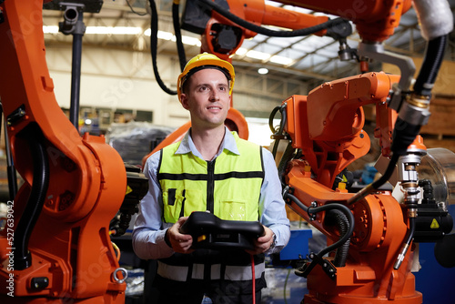 factory worker or engineer operating remote switch controller to control robot machine in the factory