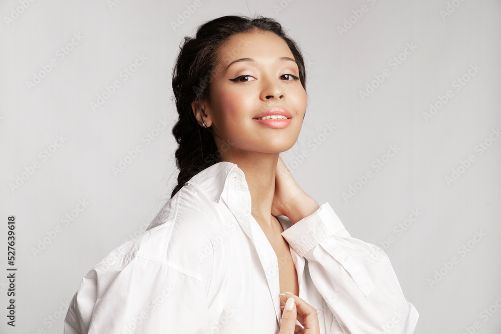 Beautiful black girl wearing white shirt with healthy glowing skin, perfect make up smiling, posing on gray studio background with copy space for advertising. Skincare treatment cosmetics ad. Beautiful black girl wearing white shirt with healthy glowing skin, perfect make up smiling, posing on gray studio background with copy space for advertising. Skincare treatment cosmetics ad.