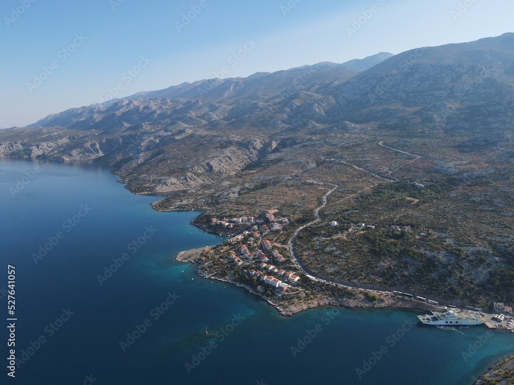 Aerial view of Prizna, Trajekt Prizna-Zigljen to reach the island of Pag. Drone view of queue to catch ferry for Pag. Small town with turquoise water on the hill of Croatia, in Dalmatia.