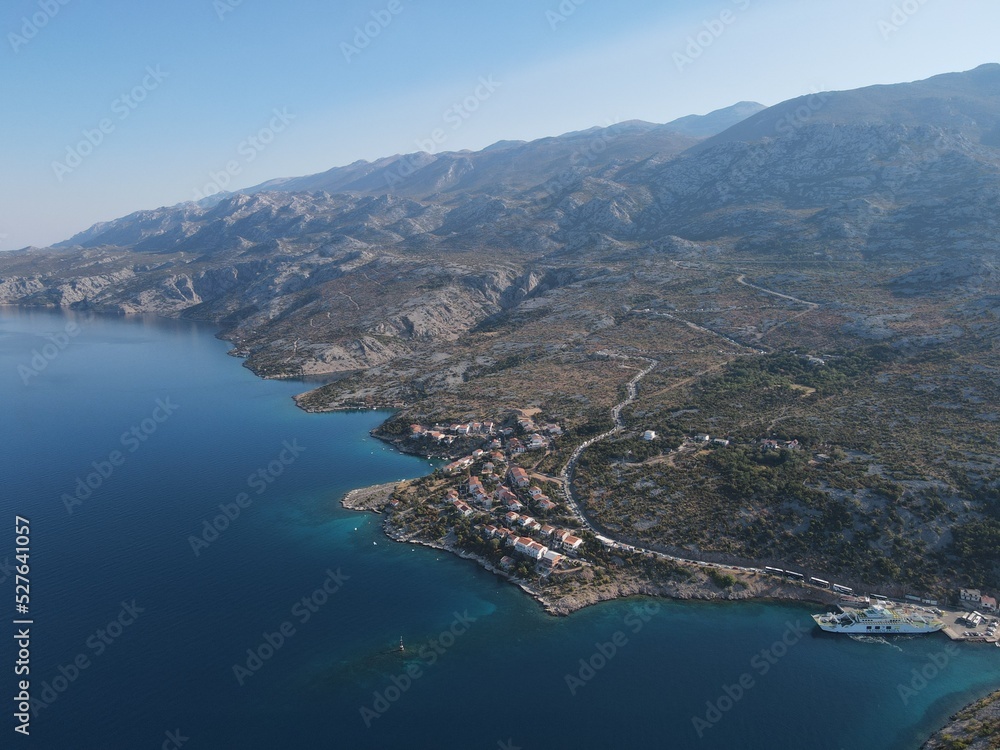 Fototapeta premium Aerial view of Prizna, Trajekt Prizna-Zigljen to reach the island of Pag. Drone view of queue to catch ferry for Pag. Small town with turquoise water on the hill of Croatia, in Dalmatia.