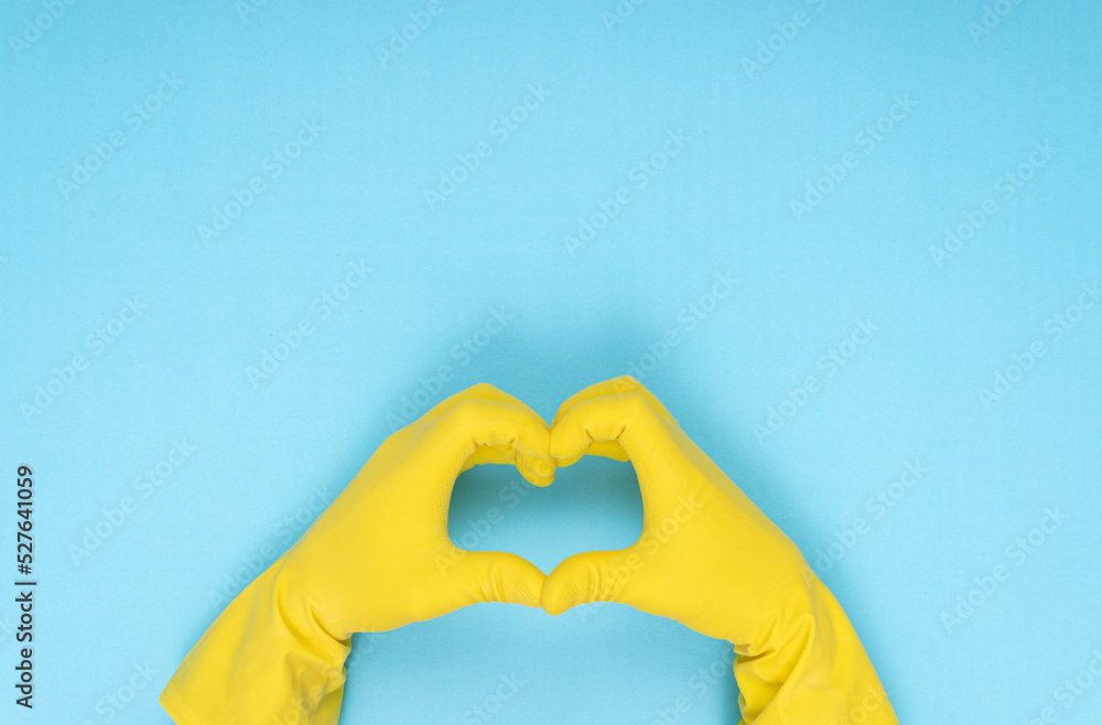 hands making heart shape with yellow cleaning glove on blue background hands making heart shape with yellow cleaning glove on blue background
