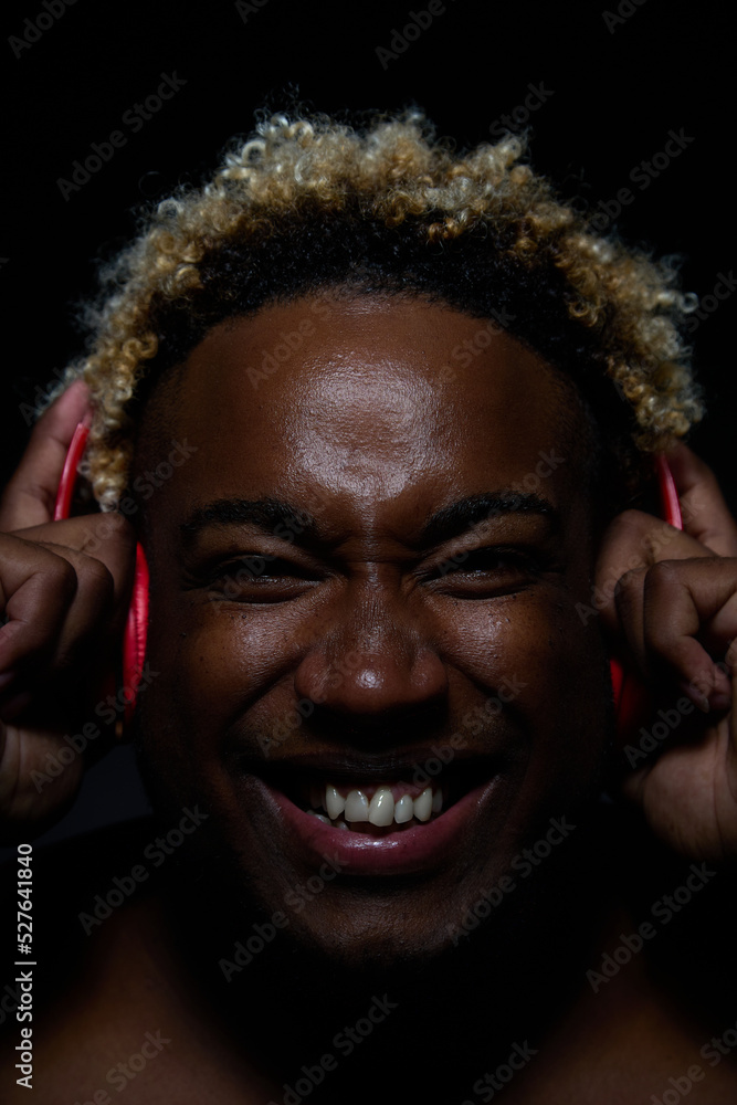 An African American man is delighted with the music he listens to in red wireless on a black background An African American man is delighted with the music he listens to in red wireless on a black background
