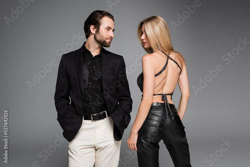 Bild auf Leinwand Stylish woman in leather pants standing near boyfriend isolated on grey