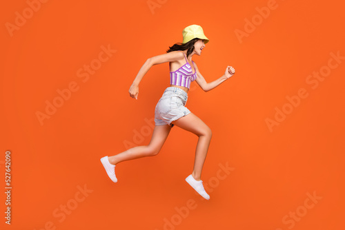 Full length photo of hurrying woman dressed violet bra jumping high running fast isolated orange color background