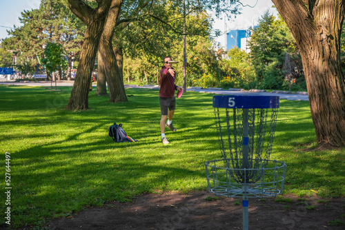 Disc golf, a flying disc sport played using rules like golf, being played by a middle aged man on a nine hole course in  Ashbridges Bay Park in Toronto’s Beaches neighbourhood in late August. photo