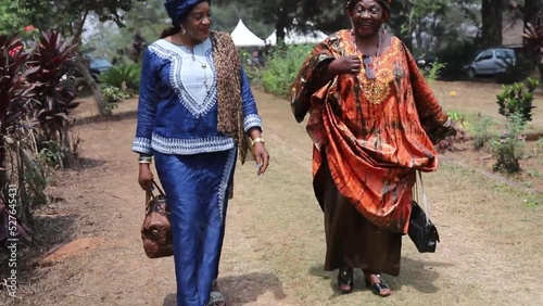 Two African women walk while having a conversation, they are traditionally dressed photo