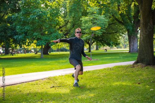 Sticker Disc golf, a flying disc sport played using rules like golf, being played by a middle aged man on a nine hole course in  Ashbridges Bay Park in Toronto’s Beaches neighbourhood in late August