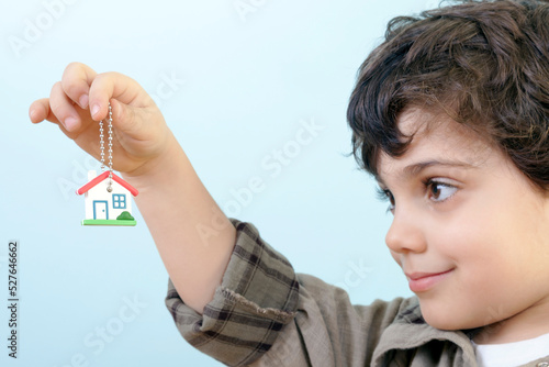 Little Boy is Looking to a House Key Against Blue