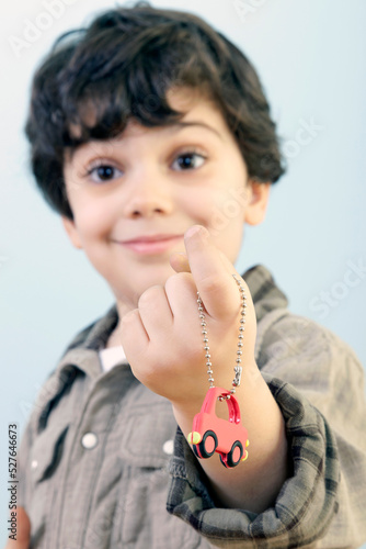 Boy is Showing Us a Car Key Against Blue Background