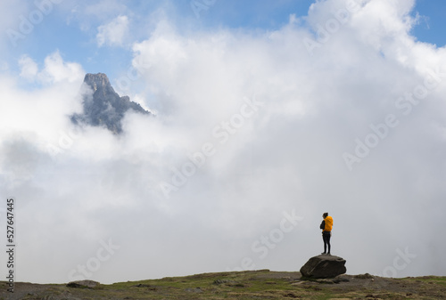 Girl with orange backpack looking at the Midi dOssau mountain in the Pyrenees National Park, France. photo