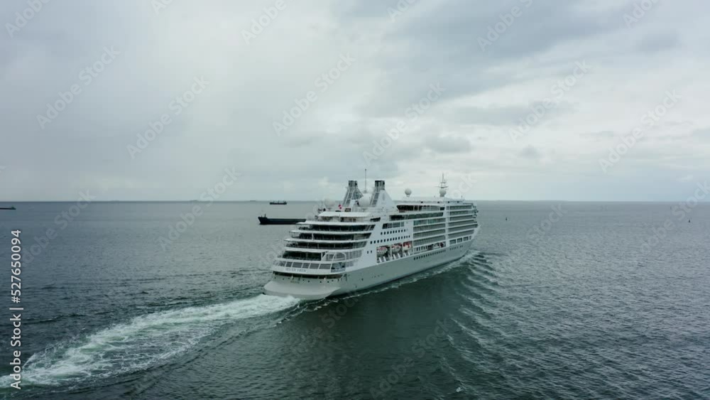 Cruise ship sailing on the Baltic Sea in stormy weather with rain. cruise ship sails to Norway. People on the upper deck are celebrating their holidays. Aerial view of cruise liner Summer sea travel Cruise ship sailing on the Baltic Sea in stormy weather with rain. cruise ship sails to Norway. People on the upper deck are celebrating their holidays. Aerial view of cruise liner Summer sea travel