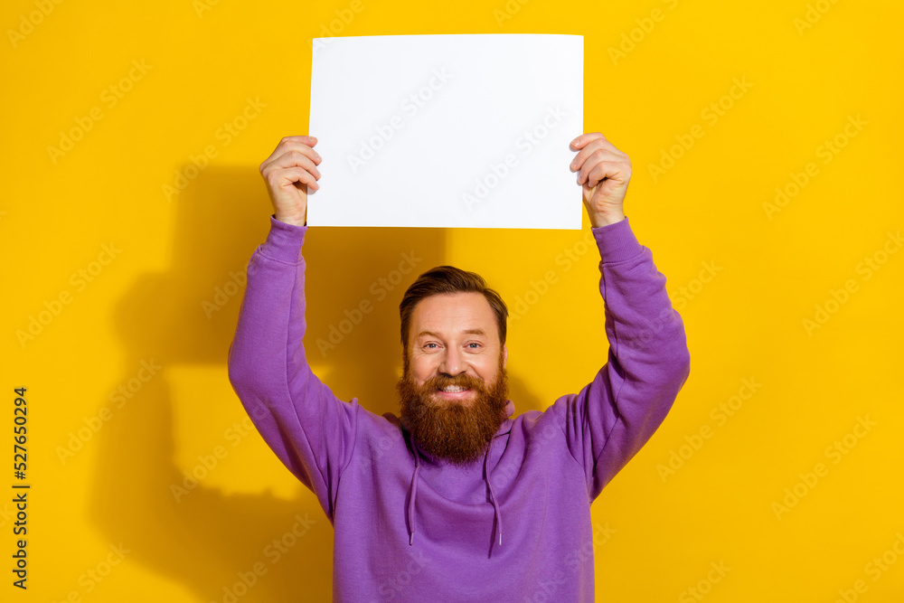 Portrait of cheerful excited person arms hold empty space paper above head isolated on yellow color background Portrait of cheerful excited person arms hold empty space paper above head isolated on yellow color background
