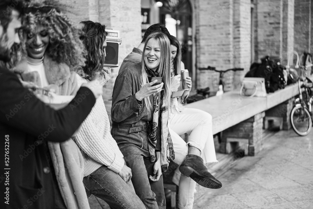 Obraz premium Group of friends having fun listening playlist music in boombox stereo outdoor - Focus on center girl face - Black and white editing
