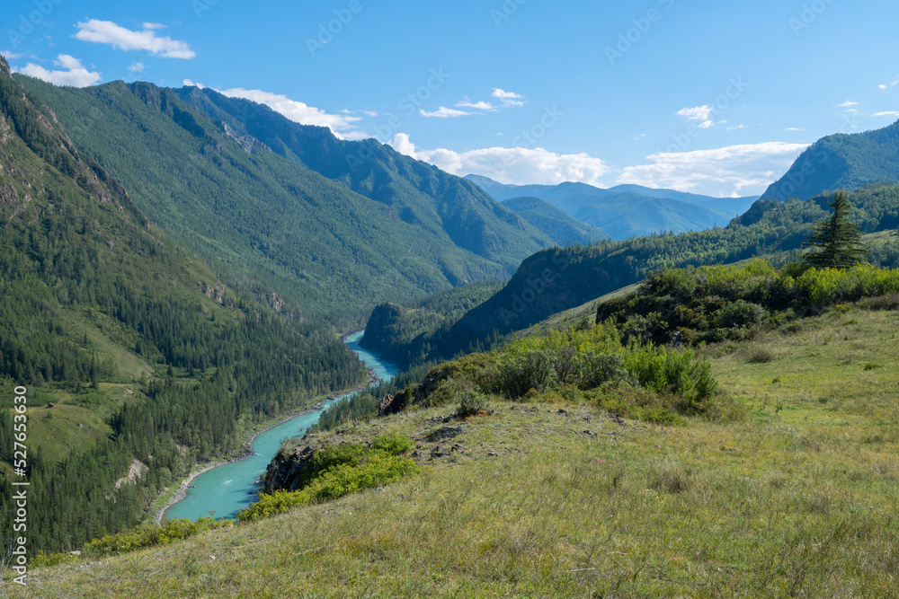 alpine landscape of a valley with a turquoise river from the top of a mountain, a hill in clear sunny weather