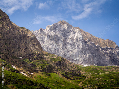 Montaña rocosa de los Pirineos bajo un cielo azul con angunas nubes blancas.