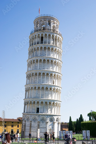 Pisa, Toscana , Italia 08-28-2022.  A picturesque portrait shot of the famous Pisa Leaning Tower on a beautiful day at dusk with a blue sky, and the sun shines on the white marbled campanile.