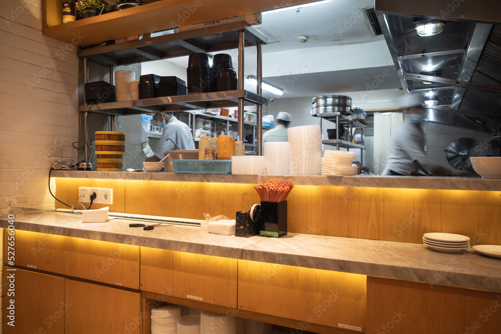 Kitchen of an Asian cuisine restaurant with staff busy cooking and working on the background Kitchen of an Asian cuisine restaurant with staff busy cooking and working on the background
