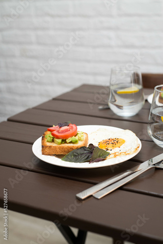The table with breakfast of sandwiches and fried eggs, glasses of water with lemon.