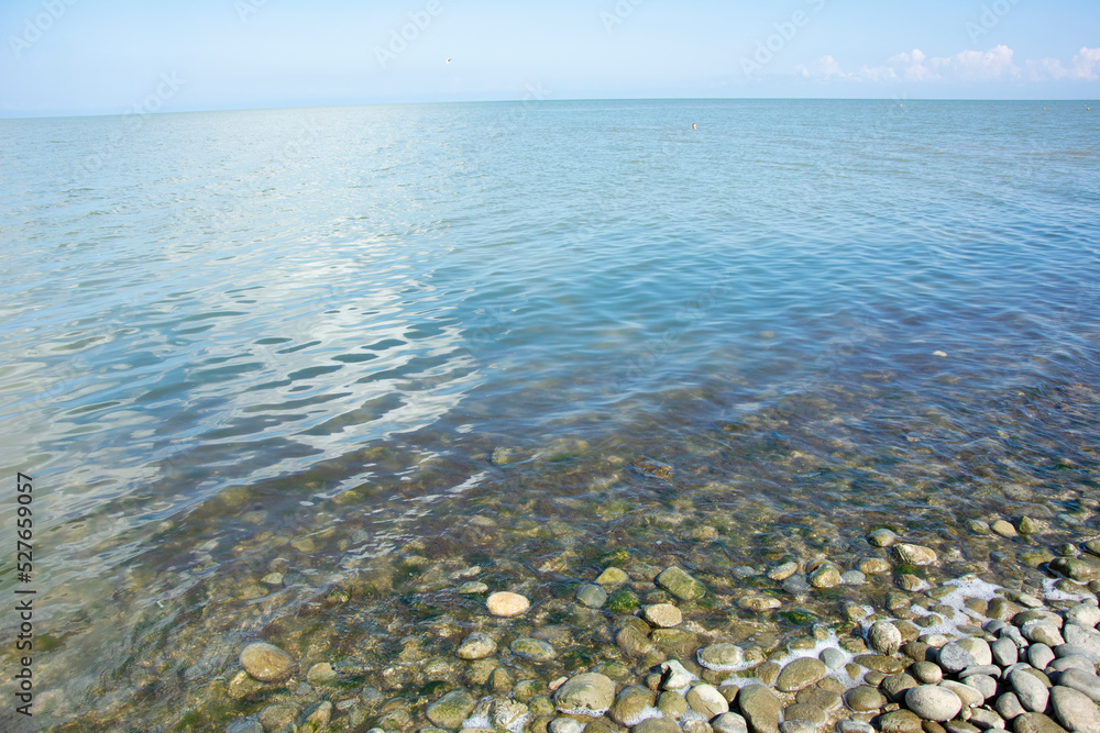 Calm sea with clear water and pebbles near the shore on a sunny summer day. Place for text. Calm sea with clear water and pebbles near the shore on a sunny summer day. Place for text.