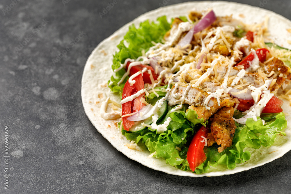 Flatbread, Tortilla with chicken meat, lettuce, tomatoes, cheese, sauce. Easy to cook sandwich on dark background. Healthy snack. Flatbread, Tortilla with chicken meat, lettuce, tomatoes, cheese, sauce. Easy to cook sandwich on dark background. Healthy snack.