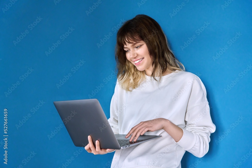 Young teenage female with laptop on blue background Young teenage female with laptop on blue background