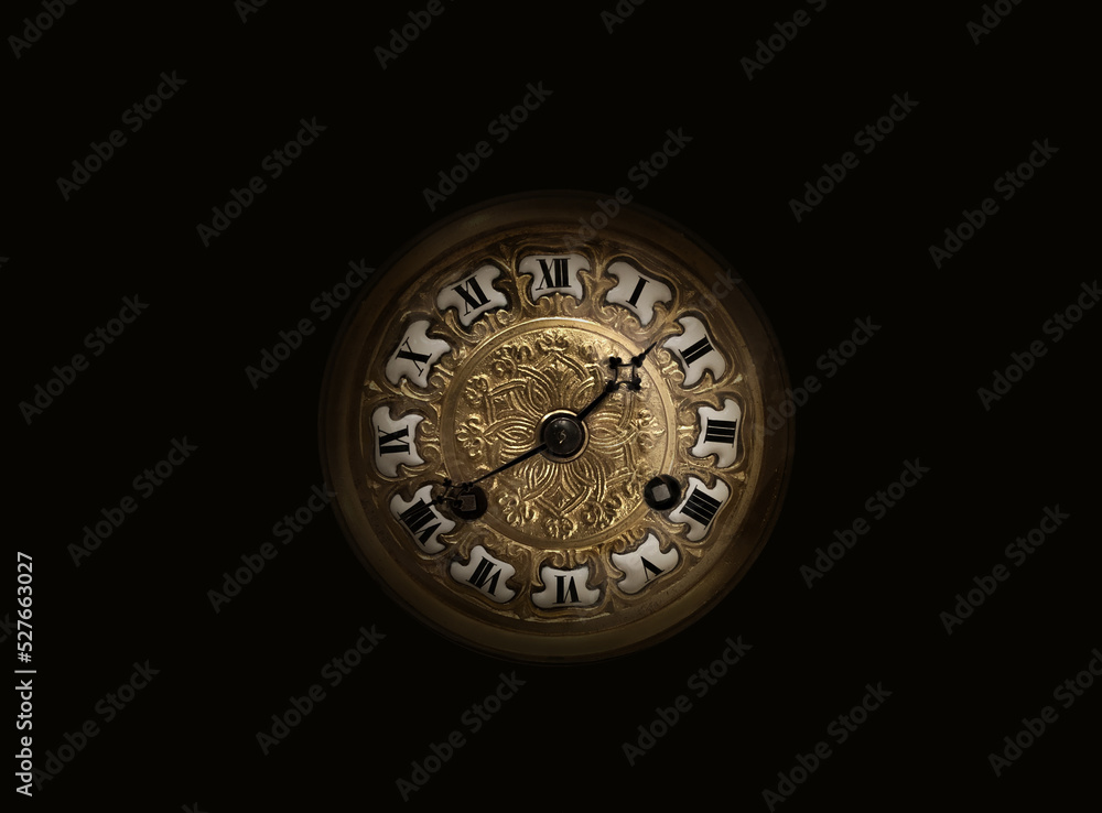 An old antique clock with roman numerals on the dial, isolated on black
