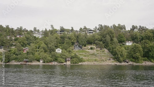 Natural landscape with rippling river and houses by the coast. Action. Countryside region, view from the river on a small town and green trees. photo