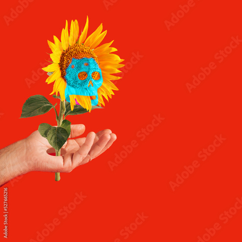 A sunflower stalk coming out of a man's palm and a skeleton head appears on an ostrich, on a red background, minimalistic concept, Halloween photo