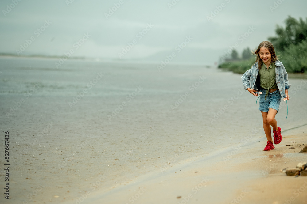 A girl on a rainy day runs along the shore