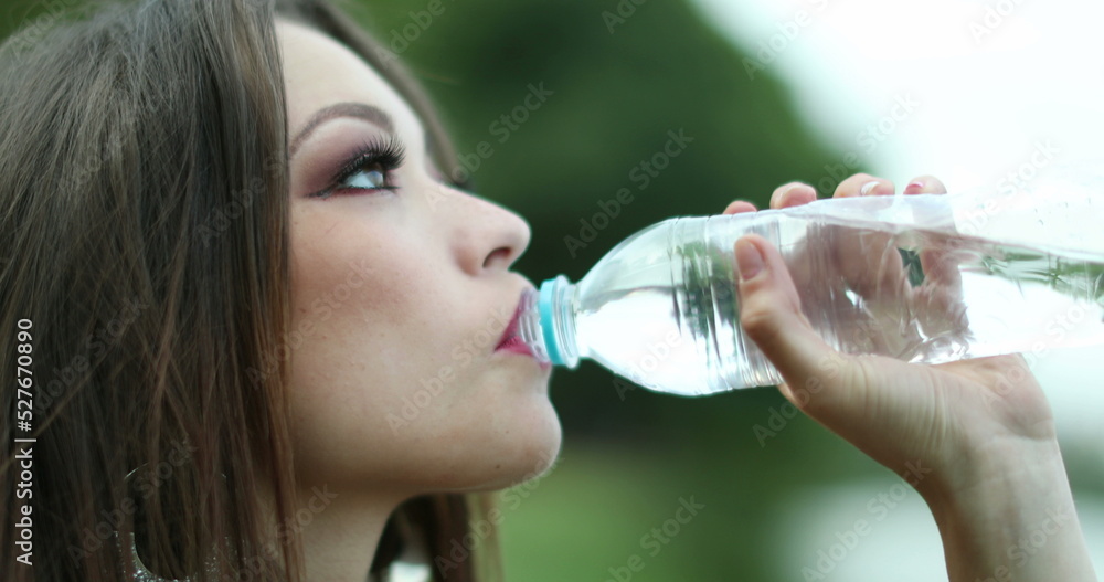 Girl drinks bottle of water outside at park Girl drinks bottle of water outside at park
