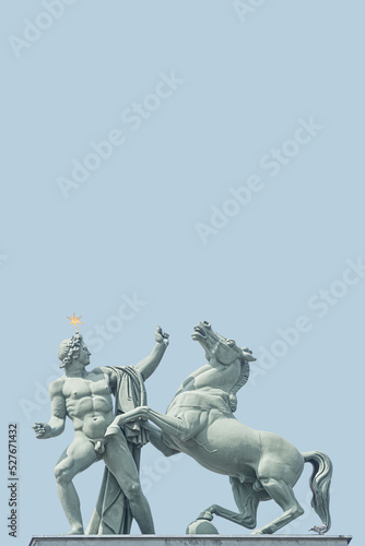 Cover page with a top roof statue at History Museum of a Roman man holding a wild horse, in historical and museum downtown of Berlin, Germany, at blue sky with copy space.