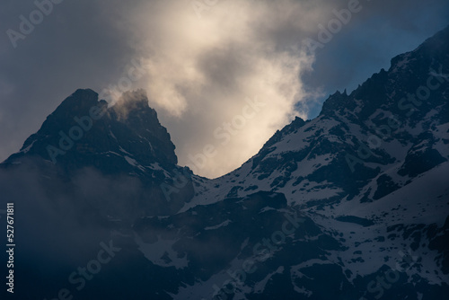 Clouds near snow covered mountain peaks