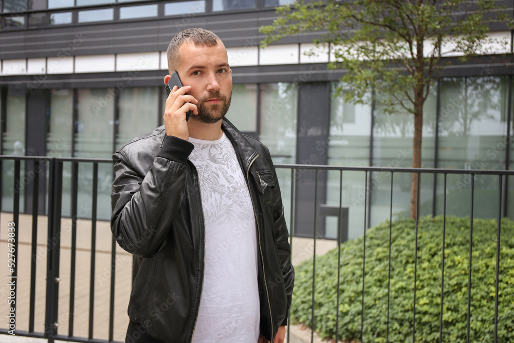 a serious man speaks on the phone against the backdrop of a developing city a serious man speaks on the phone against the backdrop of a developing city