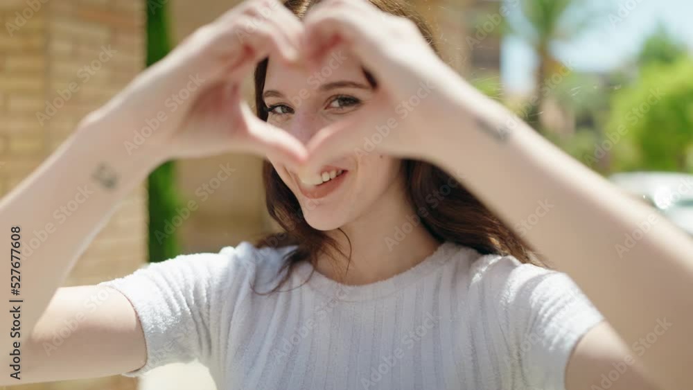 Young woman smiling confident doing heart gesture with hands at street Young woman smiling confident doing heart gesture with hands at street