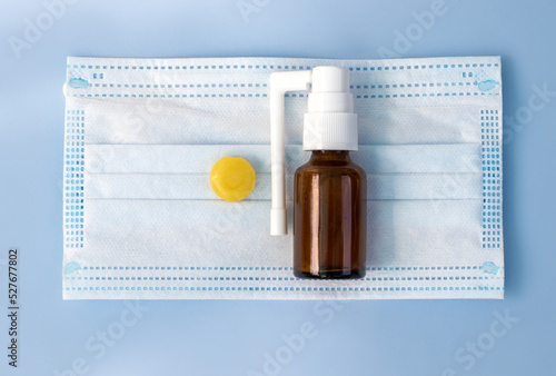 spray and lozenge pill tablet candy lemon honey ingredients isolated on surgical protection mask.anti inflammatory redness and pain treatment.isolated blue background.bacteria virus