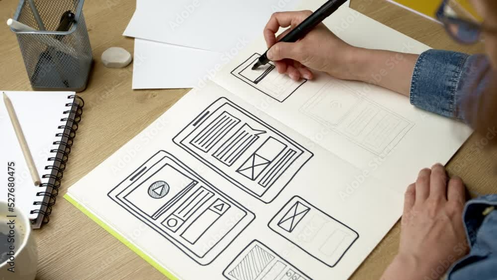 UI designer sketches the user interface of a web application for a mobile phone. A developer creates a prototype for a smartphone.