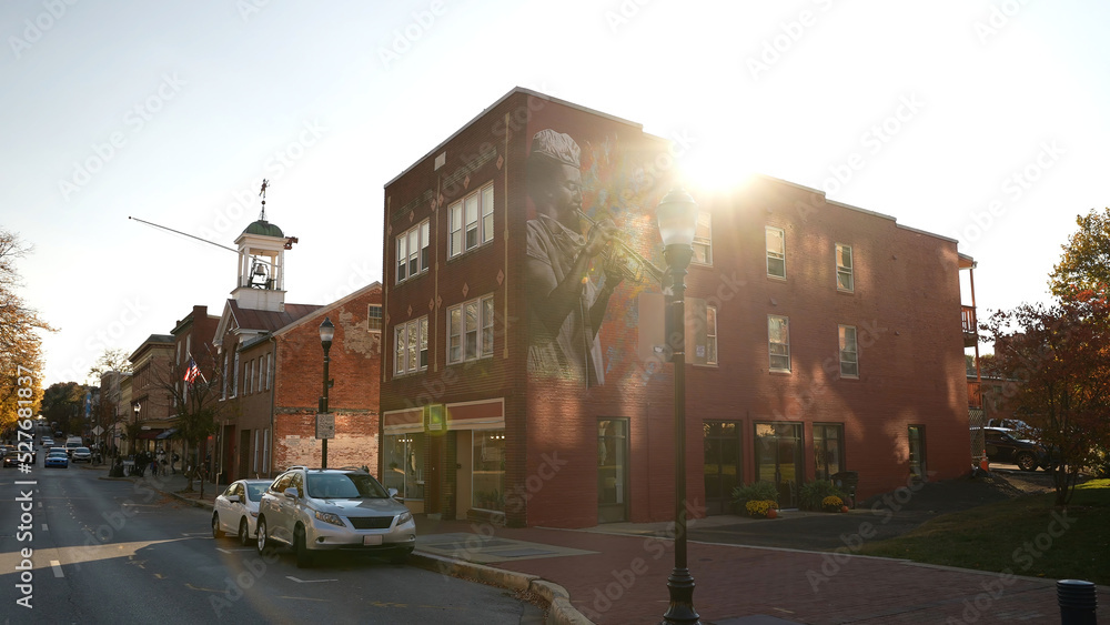 Frederick, MD, USA - 11 10 2021: An afternoon view of street in Frederick Maryland with firehouse. Old historic rural town with vintage buildings. Autumn colors dominate trees with colorful foliage.