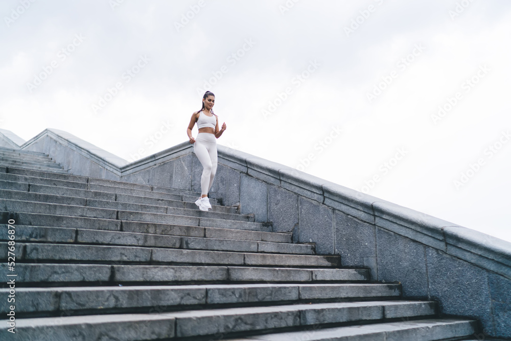 Fit young ethnic sportswoman running on staircase on street