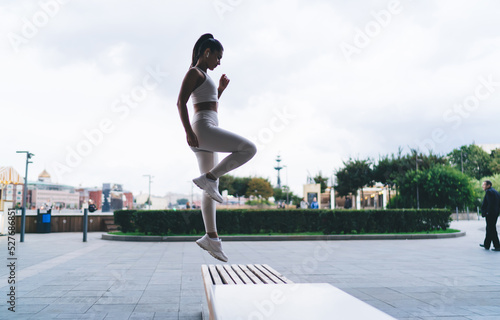 Determined sportswoman doing step ups on bench on street