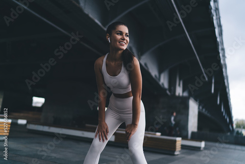 Happy Hispanic female athlete smiling while resting during workout on street