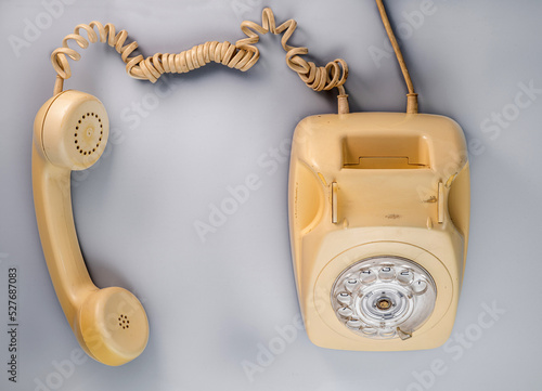 Fotografía Old yellow antique rotary telephone with removed receiver on blue background