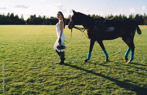 Young female rider walking horse on green lawn © BullRun