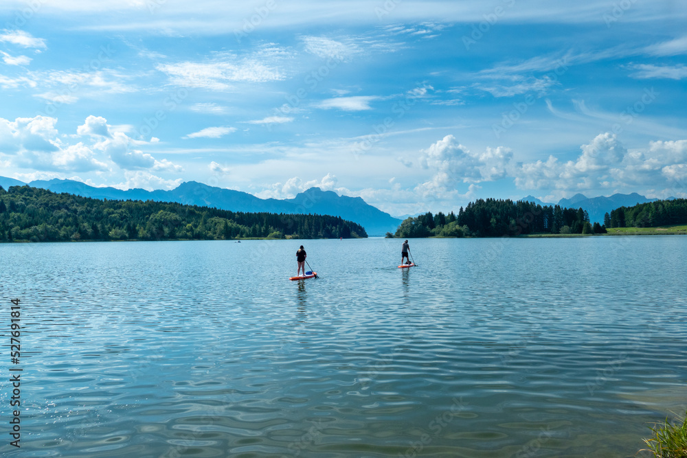 Couple at the Forggensee doing stand up paddling during summer, Bavaria Germany