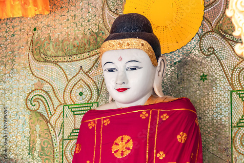 An finely crafted Buddha figure with a red robe in a temple of the Shwedagon Pagoda in Burmese Yangon photo